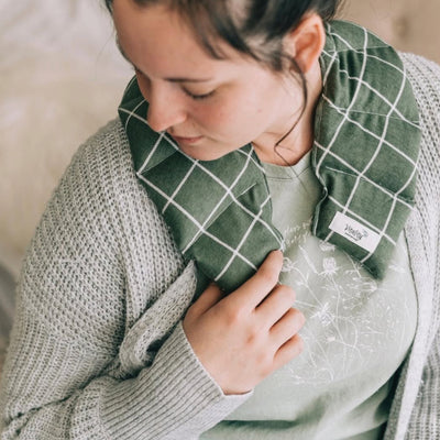 Person holding a green checkered pillow with a visible brand label.